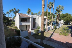 A modern two-story house with a tiled roof, surrounded by palm trees and a well-maintained lawn.