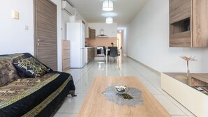 Una sala de estar moderna con un sofá, una mesa de centro y una cocina al fondo.