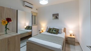 Un dormitorio moderno con cama, mesitas de noche, un espejo y aire acondicionado de pared.