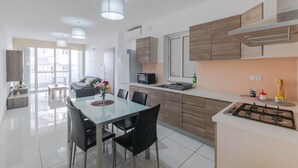 Una cocina moderna con comedor, que incluye una mesa de vidrio, sillas negras y armarios de madera.