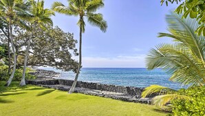 A grassy area with palm trees and a stone wall by the ocean. - Bright & Airy Beach House w/ Oceanfront Views (Kailua-Kona)