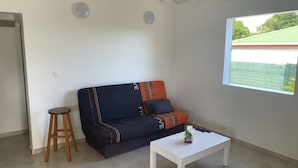 Ett rum med en soffa, en liten pall och ett vitt bord.