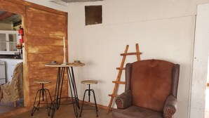 Ein Zimmer mit einem braunen Ledersessel, einer Holzleiter, einem kleinen Tisch mit Kerze und einem Hocker.