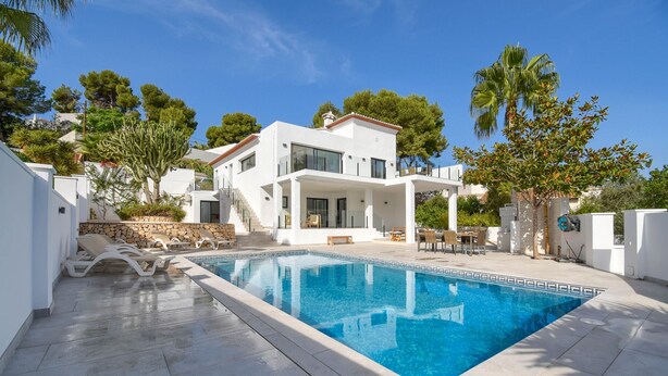 A modern two-story house with a swimming pool, surrounded by palm trees and a stone wall. - Graham Holiday Rentals - Magnolia (Moraira)