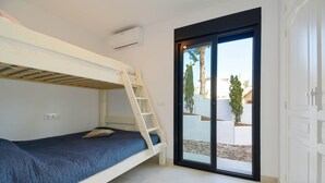 A bunk bed room with a ladder, a sliding glass door to the outside, and a white wardrobe. - Graham Holiday Rentals - Magnolia (Moraira)