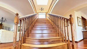 A wooden staircase with a curved design, leading to a room with a chandelier and framed pictures on the walls. - Quinta Martin, spacious villa with views of Funchal and the Atlantic Ocean  (Funchal)