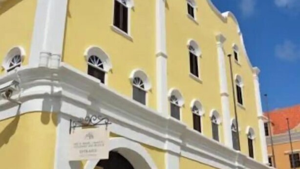 Un edificio amarillo con detalles blancos y numerosas ventanas.