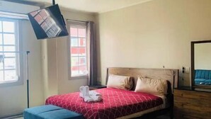 Un dormitorio con cama, mesita de noche, lámpara colgante y ventana.