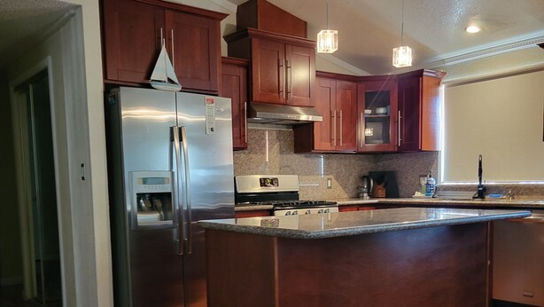 A modern kitchen with wooden cabinets, stainless steel appliances, and a large island.