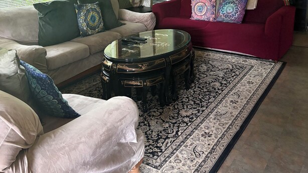 A living room with a ceiling fan, a red sofa, a beige sofa, a glass coffee table, and a patterned rug. - Spacious Home in Skagway Alaska (Skagway)