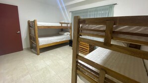 Une pièce avec deux lits superposés en bois, une porte rouge et une fenêtre avec un rideau.