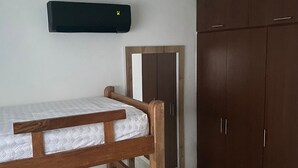 Une chambre avec un lit superposé, une armoire et un miroir.
