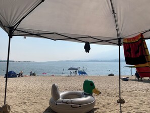 A beach with a tent, inflatable duck float, and a clear view of the water.