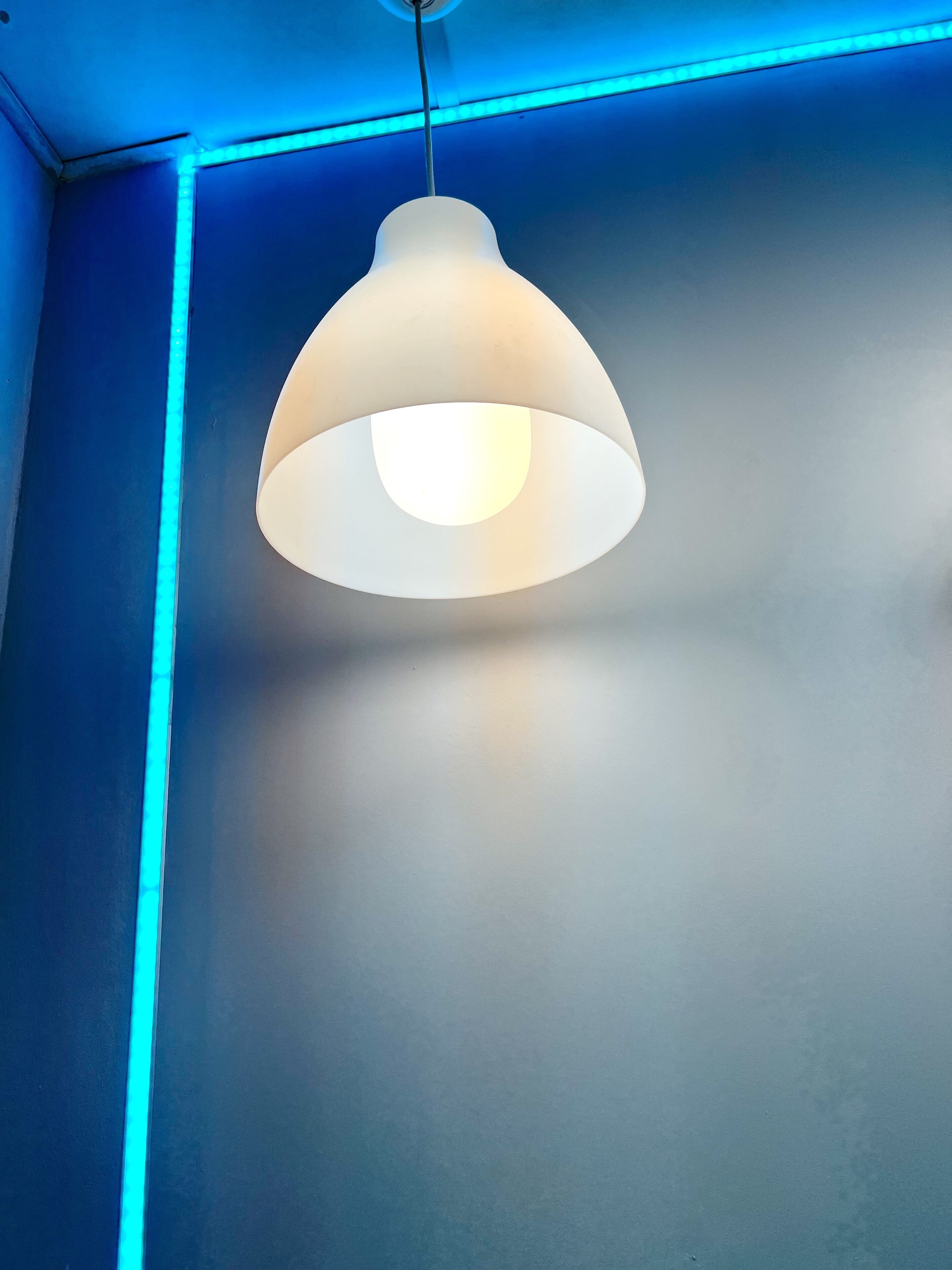 Una lámpara colgante con pantalla blanca suspendida del techo.