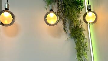Three spherical pendant lights with exposed bulbs hanging from the ceiling, surrounded by green foliage.
