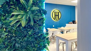 A modern office space with a vertical garden wall, a logo on the wall, and a seating area with tables and chairs. - Hostel Thirty One (Madrid)