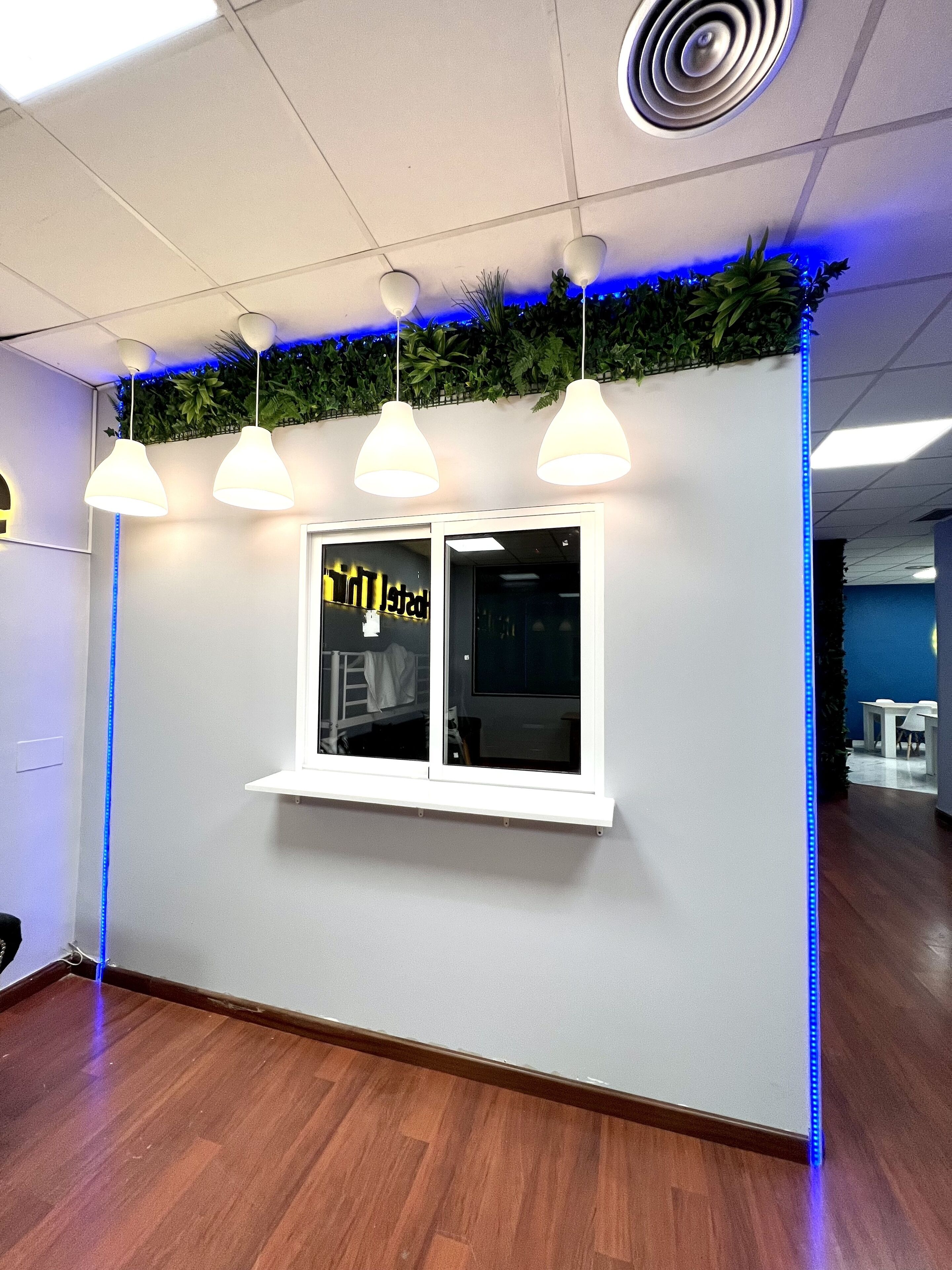 A reception area with a white wall, a window with a sign, pendant lights, and a blue LED strip.