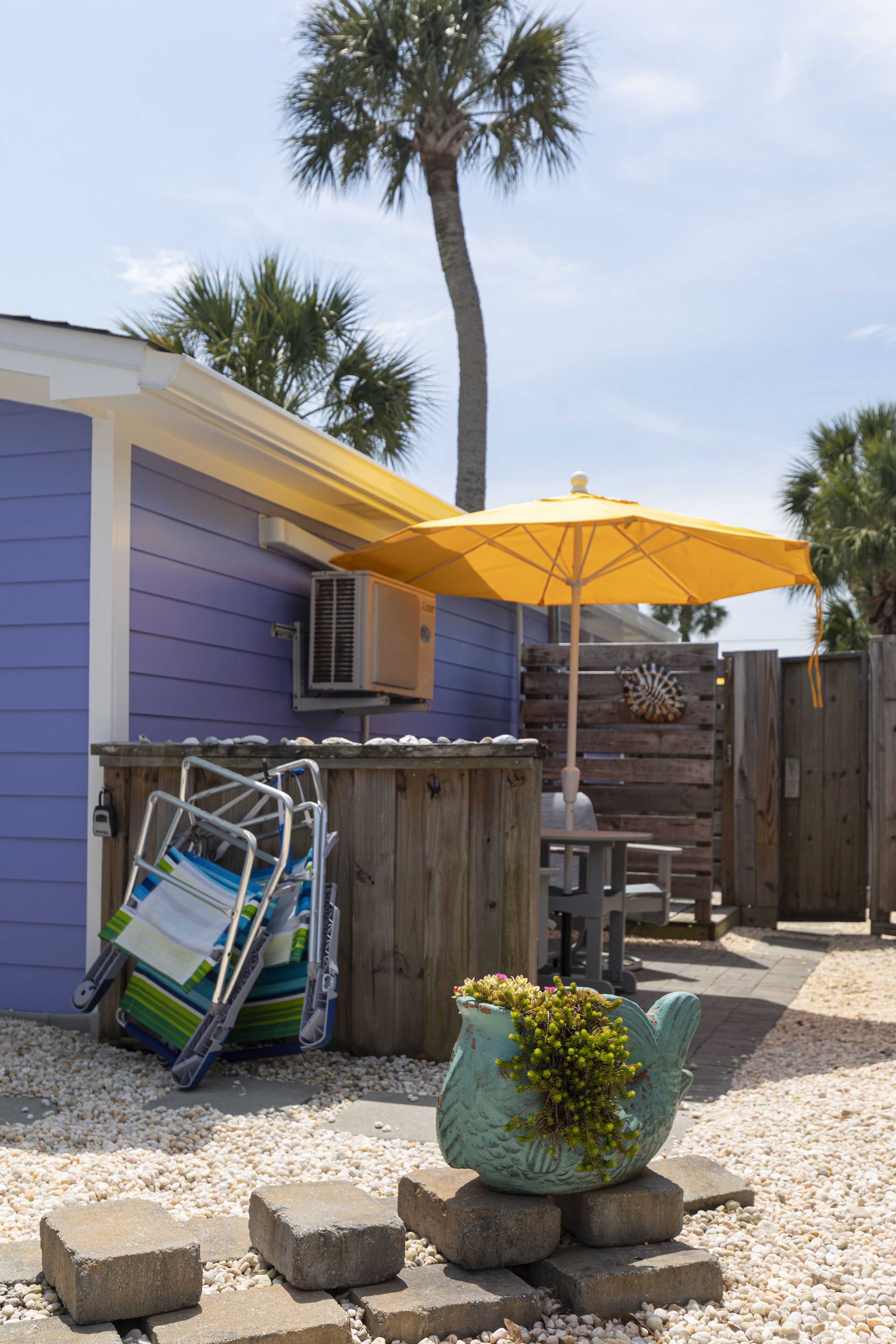 A patio area with a yellow umbrella, a wooden deck, and a decorative planter.
