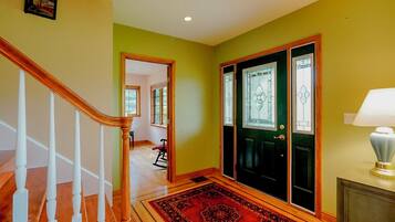 A staircase with wooden balusters leading to a landing with a red patterned rug.