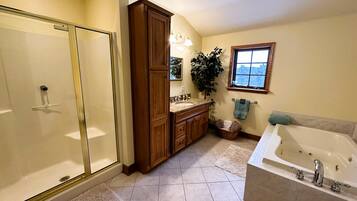A bathroom with a walk-in shower, wooden cabinets, a large bathtub, and a window with a view.