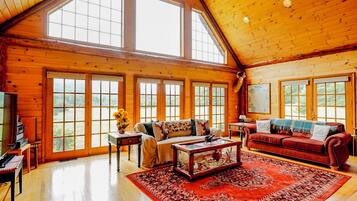 A spacious living room with large windows, a red sofa, a coffee table, and a fireplace.