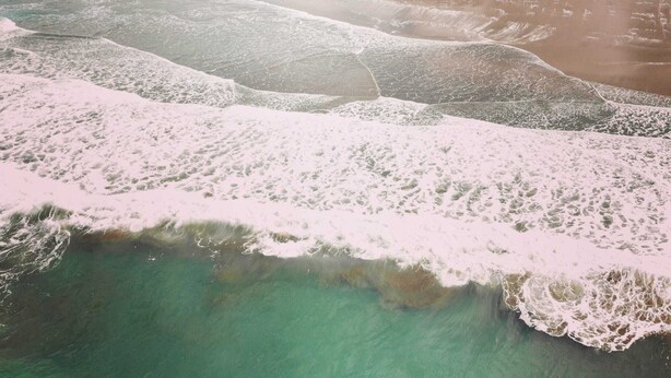 Un paisaje costero con una playa arenosa y aguas turquesas cristalinas.