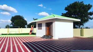 Un bâtiment doté d’un toit végétalisé et de murs blancs, d’un sol à rayures rouges et blanches, et d’une rambarde métallique.