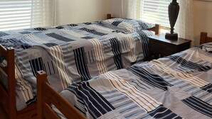 A room with two wooden beds, white curtains, a lamp on a nightstand, and a window with blinds. - Classic Old Orchard Beach Cottage One Block from the Beach (Old Orchard Beach)