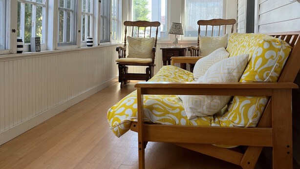 A room with a wooden bed, two chairs, a table, and large windows. - Classic Old Orchard Beach Cottage One Block from the Beach (Old Orchard Beach)
