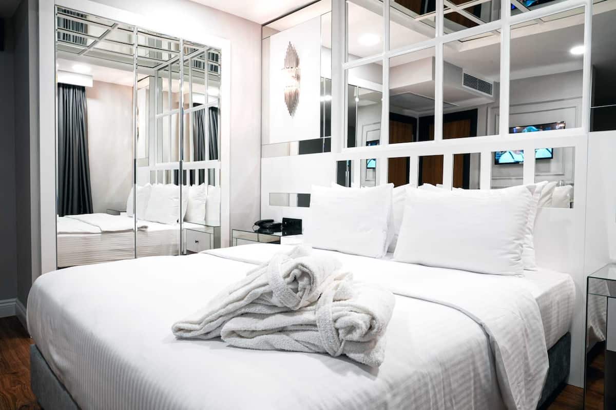Ein modernes Hotelzimmer mit einem großen Bett, einem Spiegel und einem Fernseher.