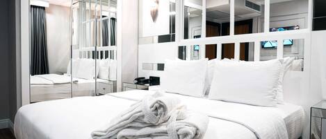 A modern hotel room with a large bed, a mirror, and a television.