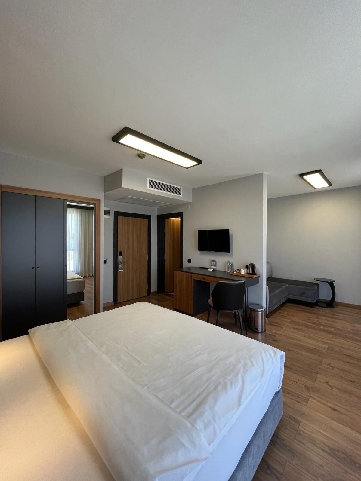 Una habitación de hotel moderna con una cama grande, un escritorio, un televisor de pantalla plana y un área de descanso.