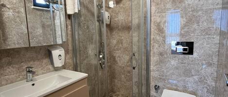 Un baño moderno con cabina de ducha de vidrio, un lavabo con espejo y baldosas de suelo con diseño.