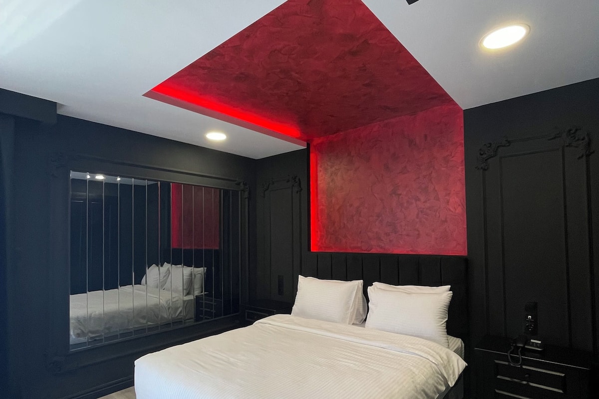 Ein modernes Schlafzimmer mit einem großen Bett, einer roten Akzentwand und einem Fenster mit Blick.