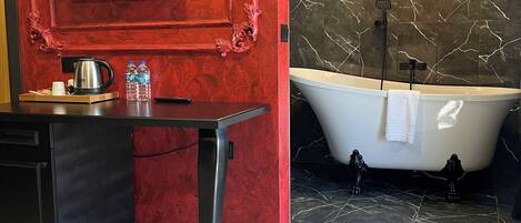 A modern bathroom with a red accent wall, a black marble backsplash, a freestanding bathtub, and a mounted TV.