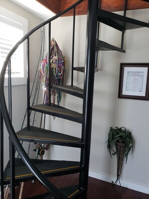 Staircase leads to an upper level with a handrail, adjacent to a framed document and a potted plant.