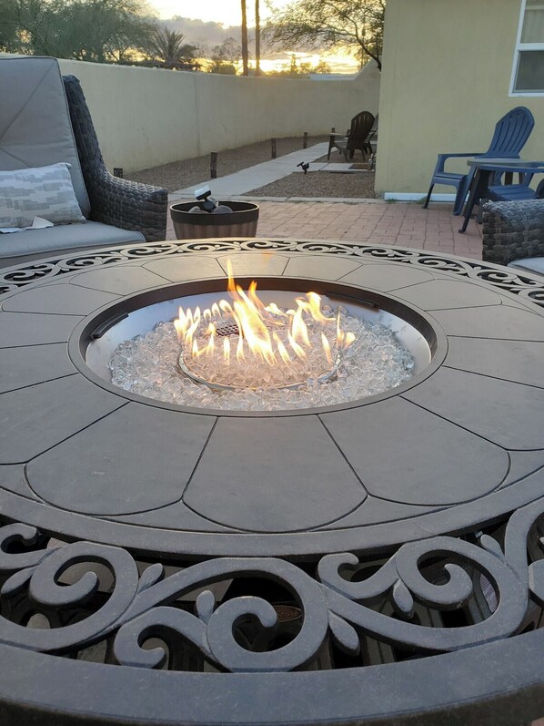 A fire pit with a decorative metal table in the center, surrounded by outdoor seating. - UofA Tiny House + Fire Pit (Tucson)