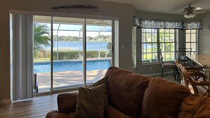 A living room with a view of a swimming pool and a patio area.