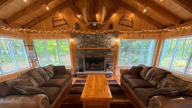 Un intérieur de chalet chaleureux avec une cheminée en pierre, des canapés en cuir et une table basse en bois.