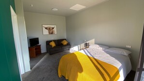 A bedroom with a bed, a sofa, a television, and a painting on the wall.