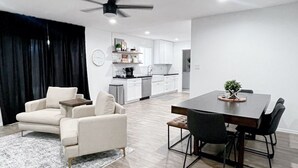 A modern living room with a dining area, a kitchen in the background, and a ceiling fan. - Modern Home with Private Pool (Phoenix)
