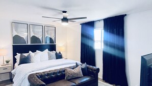 A modern bedroom with a bed, a leather sofa, a ceiling fan, and a TV. - Modern Home with Private Pool (Phoenix)