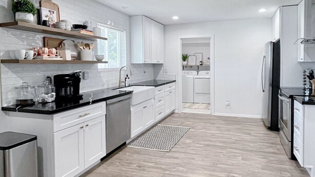 A modern kitchen with white cabinetry, a black countertop, and stainless steel appliances. - Modern Home with Private Pool (Phoenix)