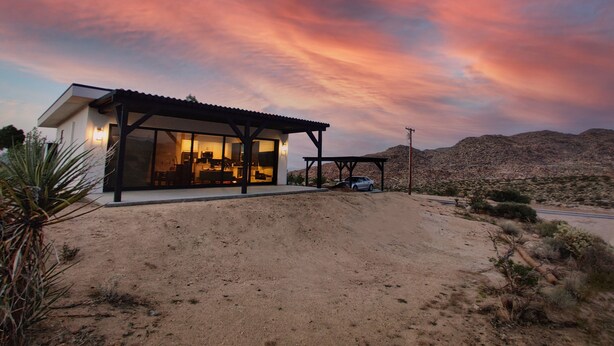 A modern house with a large glass facade, a covered patio, and a desert landscape in the background. - Joshua Tree Monochrome - 5 mins from National Park (Joshua Tree)