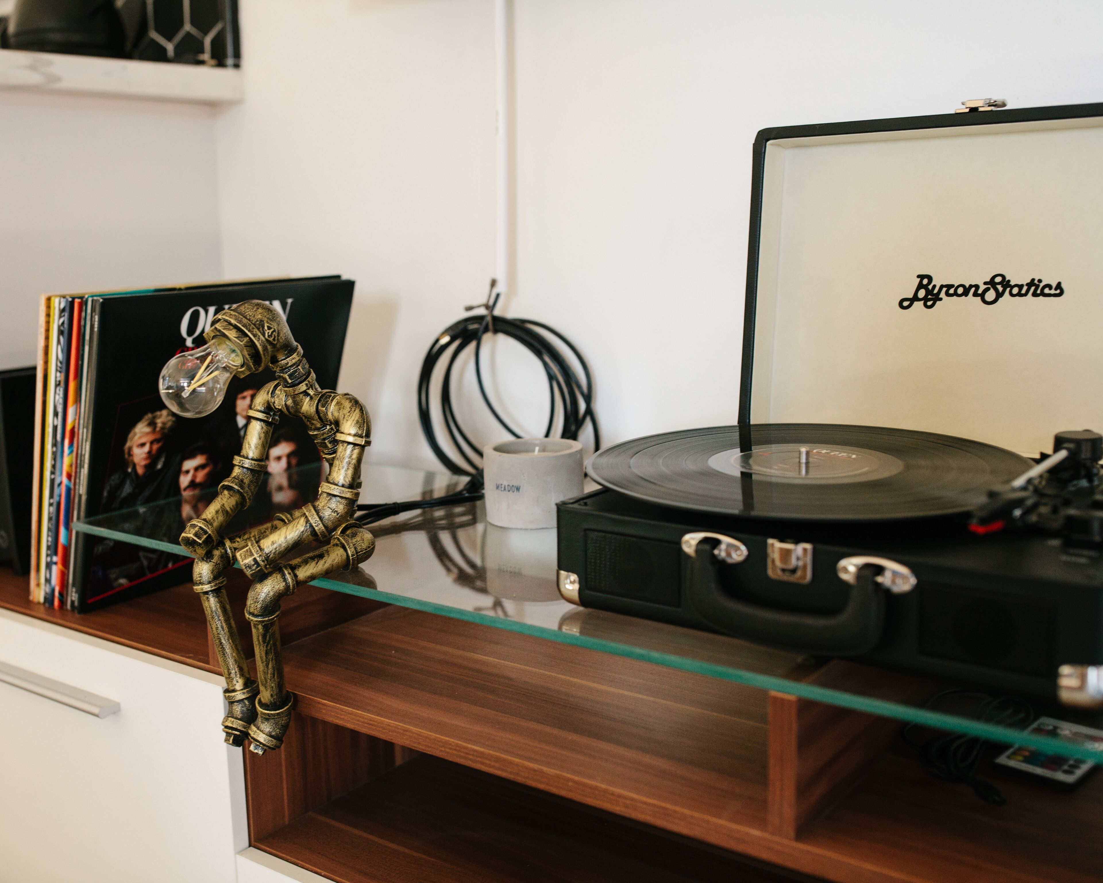 A room with a glass table displaying a vinyl record player, a record, and a decorative lamp.