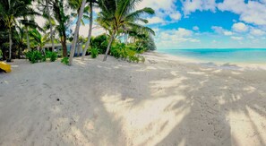 Ein Strand mit weißem Sand, Palmen und blauem Himmel.