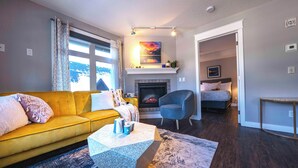 A modern living room with a yellow sofa, a fireplace, and a view of the outdoors.