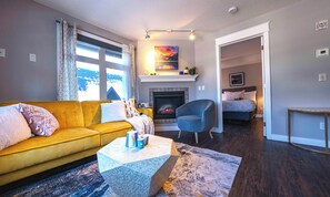 Uma sala de estar moderna com um sofá amarelo, uma lareira e vista para o exterior.