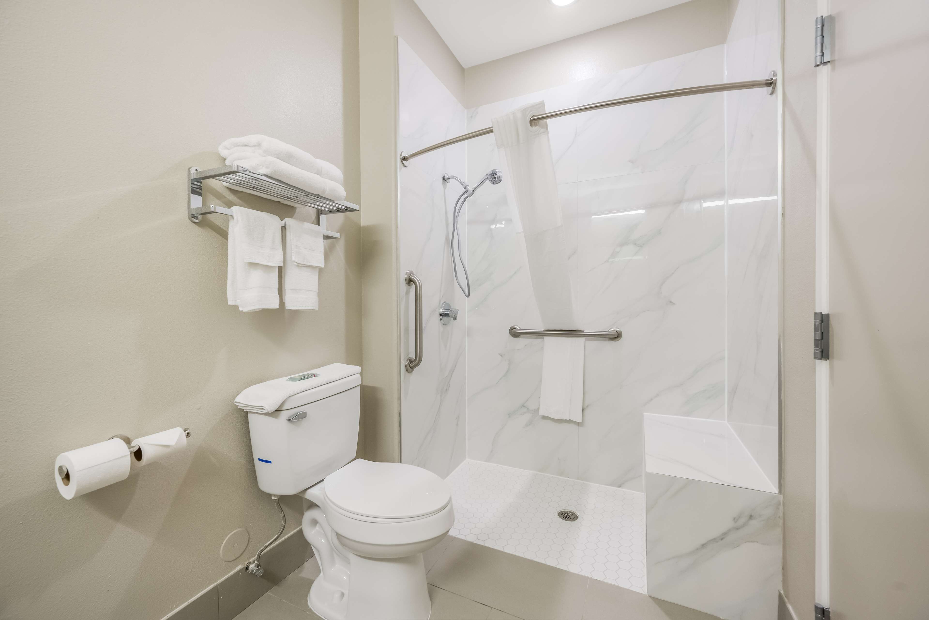 A modern bathroom with a toilet, a shower with a glass door, and a towel rack with towels.