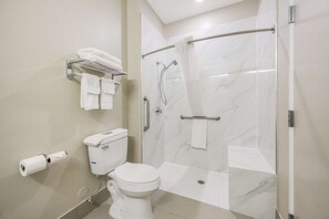 A modern bathroom with a toilet, a shower with a glass door, and a towel rack with towels.